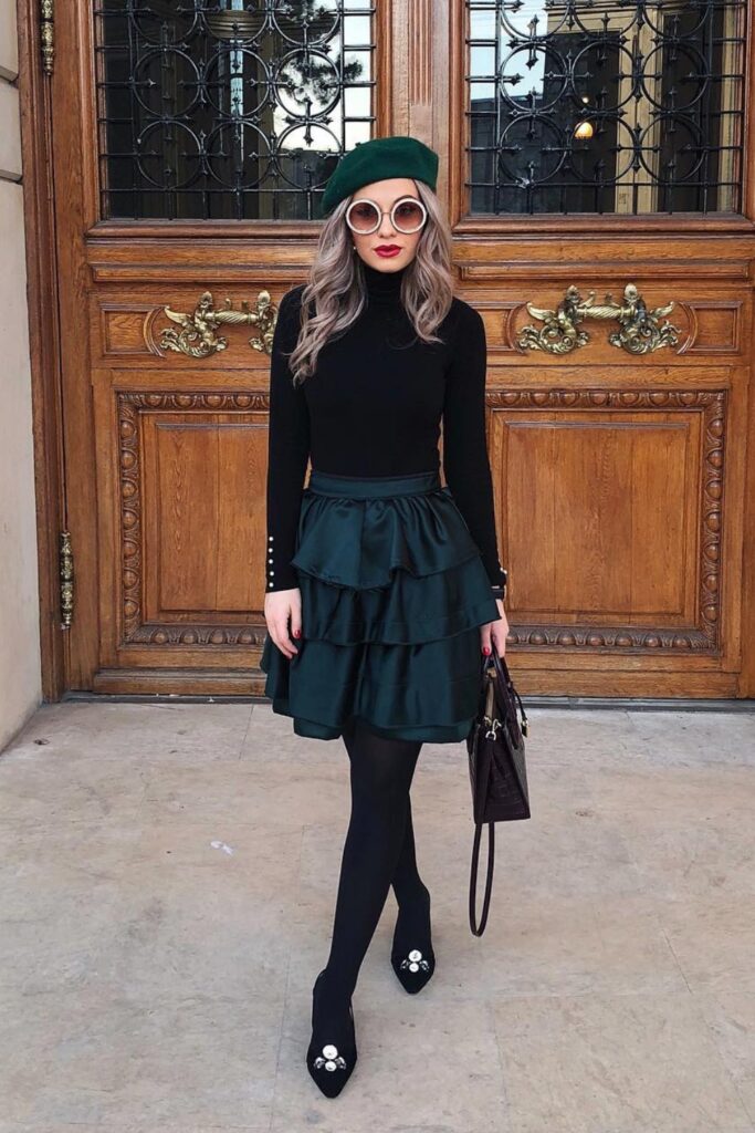 Black turtleneck sweater, dark tiered mini skirt, black tights, and black embellished kitten heels